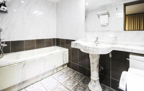 y baño blanco con lavabo y bañera. en Uljin Grand Hotel en Uljin