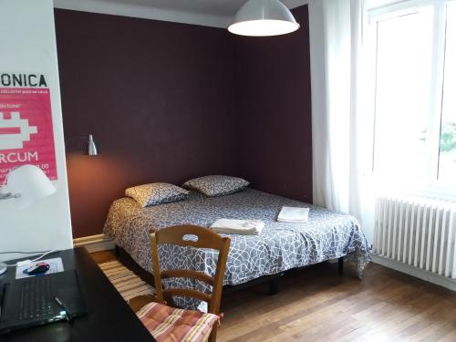 a bedroom with a bed and a desk with a laptop at Chambres Zola in Nantes