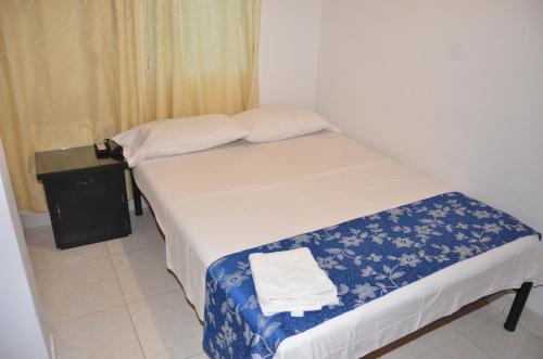 a small bedroom with a bed and a small table at Hotel Bahía Cadi in Puerto López