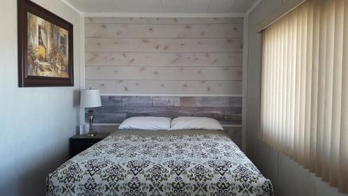 um quarto com uma cama e uma parede de madeira em Sunset motel em Portage La Prairie