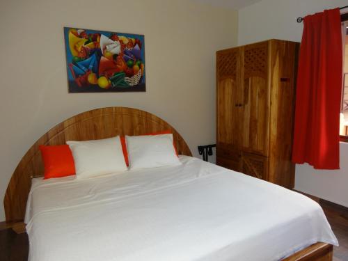 a bedroom with a bed with white sheets and orange pillows at Hotel-Boutique Patampa in David