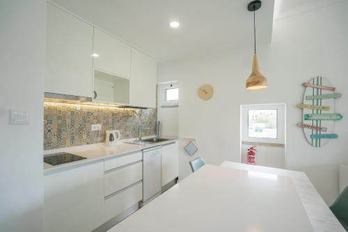 uma cozinha branca com armários brancos e um lavatório em Casas da Avó IV em Silveira
