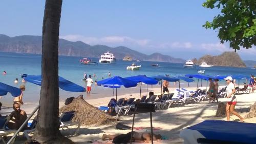 a beach with people sitting in chairs and umbrellas at Mapi's House in Paquera