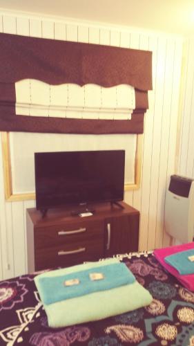 a bedroom with a bed and a dresser with a television at Cabañas Avenida España in Punta Arenas