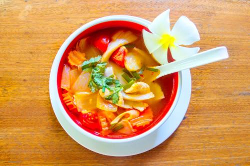 a bowl of soup with a flower on a table at Khao Sok Palmview Resort in Khao Sok