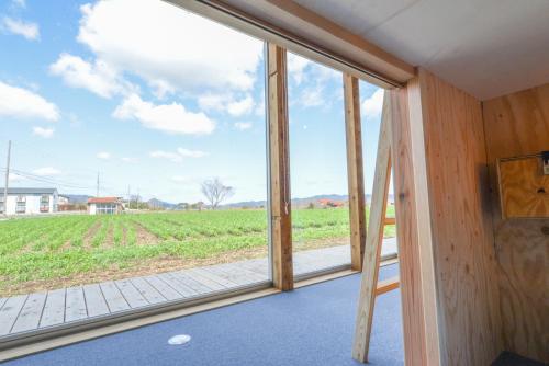 a room with a large window with a view of a field at COCORETO The Guesthouse Daikon Island in Matsue