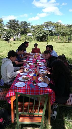 a group of people sitting at a table eating food at Oldarpoi Wageni Camps in Keekorok