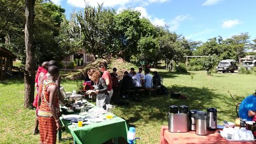 a group of people standing around tables in a field at Oldarpoi Wageni Camps in Keekorok