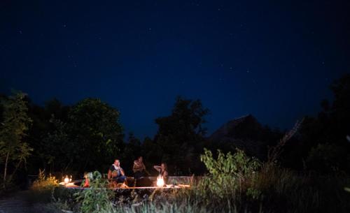 a group of people standing around a fire at night at Utopia Rote Lodge in Nembrala