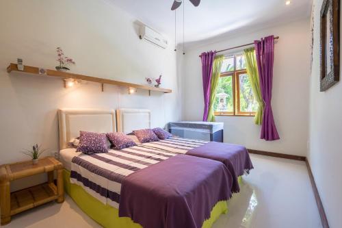 una camera da letto con un grande letto con cuscini viola di Dennis Holiday Bungalow a Jasri