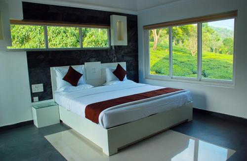 1 dormitorio con 1 cama grande y 2 ventanas en Gruenberg Tea Plantation Haus, en Munnar