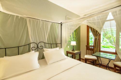 une chambre avec un grand lit avec des oreillers blancs dans l'établissement Mediterraneo Boutique Hotel, à Dar es Salaam