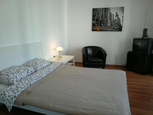 sypialnia z łóżkiem, krzesłem i telewizorem w obiekcie Trakai White Apartments w mieście Troki