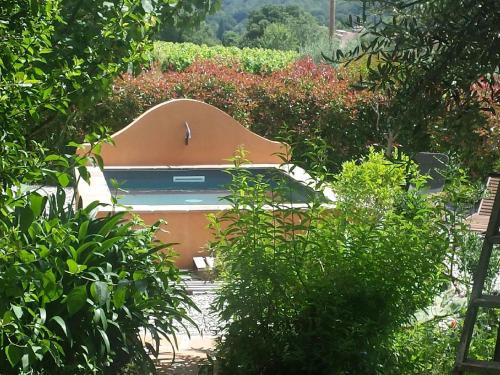 une piscine au milieu d'un jardin avec des buissons dans l'établissement Les anes de petit jean, à Pierrefeu-du-Var