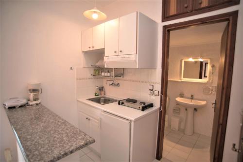 una pequeña cocina con armarios blancos y fregadero en Grammatoula, en Nikiana