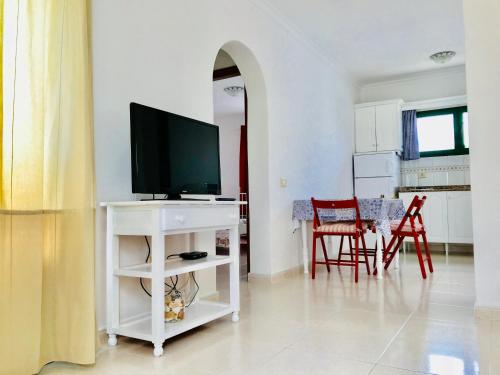 a living room with a television on a white stand at Apartamentos Flamboyant Adults Only in Puerto del Carmen