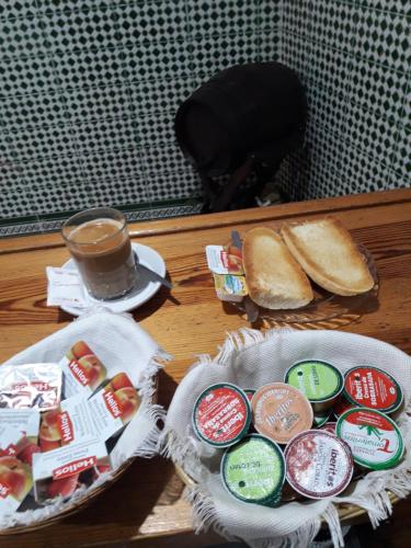 a table with a plate of sandwiches and a cup of coffee at Hostal Centro Sol in Cádiz