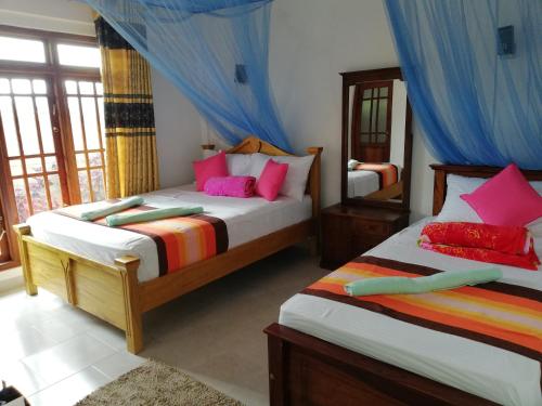 a bedroom with two beds and a mirror at Ella Jayamali Homestay in Ella