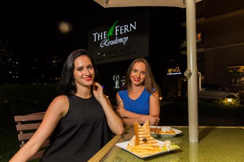 two women sitting at a table with a plate of food at The Fern Residency, Miramar in Panaji