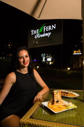 a woman sitting at a table with a plate of food at The Fern Residency, Miramar in Panaji