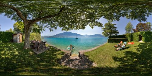 a painting of people sitting on the grass near the water at Ferienhof Margarethengut in Unterach am Attersee