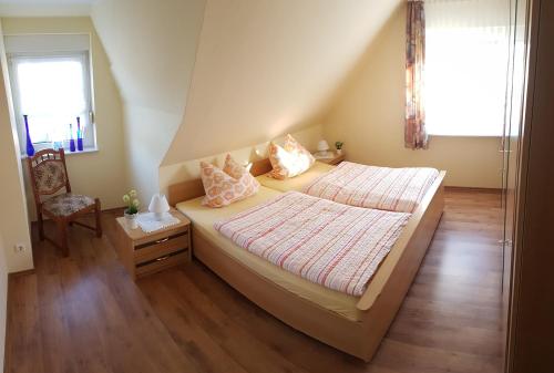 a bedroom with a bed and a chair and a window at Café Hausnordlicht - Ferienwohnung 2 in Dornum