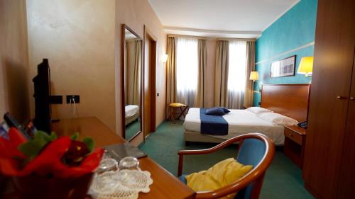 ein Hotelzimmer mit einem Bett, einem Schreibtisch und einem Tisch in der Unterkunft Classic Hotel Tulipano in Terni
