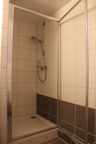 La salle de bains est pourvue d'une douche avec une porte en verre. dans l'établissement Gästehaus Chaplin, à Kempten