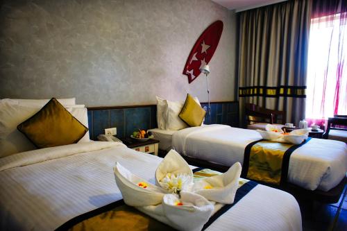 a hotel room with two beds with flowers on them at The Fern Residency, Miramar in Panaji