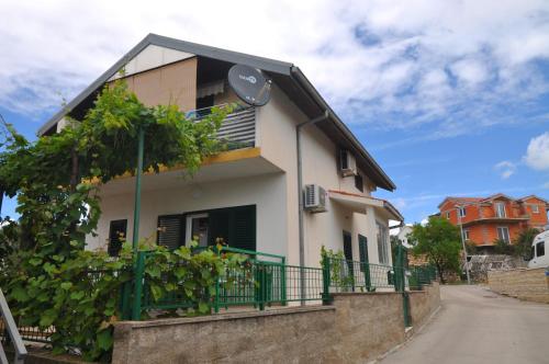 a white house with a green fence next to a street at Apartment Gatti Grassi in Zaboric