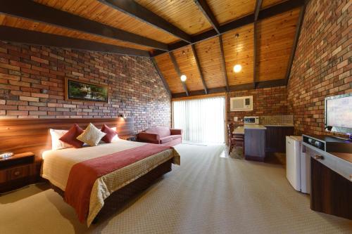 - une chambre avec un lit et un mur en briques dans l'établissement Belvoir Village Motel & Apartments Wodonga, à Wodonga