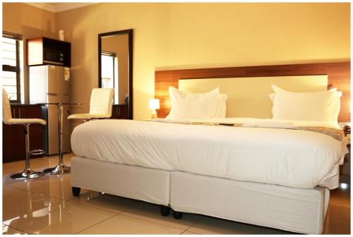 a bedroom with a large bed with white sheets and pillows at Eagle Nest Luxury Accommodation in Roodepoort