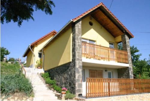 薩爾瓦爾的住宿－Panoráma Apartmanház，黄色的小房子设有阳台和楼梯
