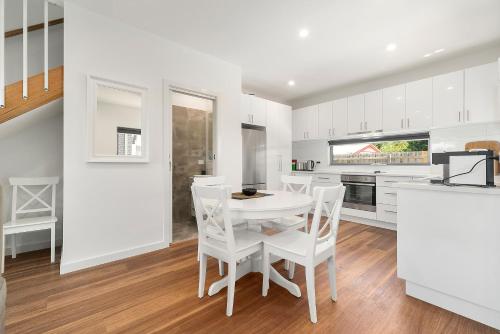 a white kitchen with a white table and chairs at Rosewater Townhouses Dromana in Dromana