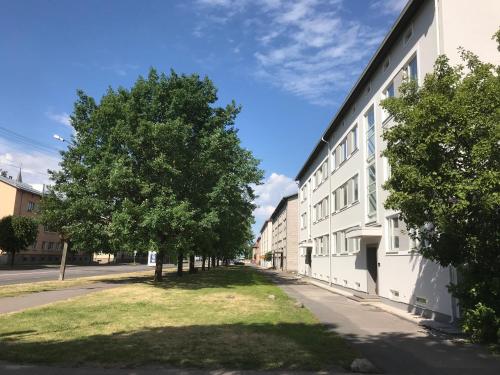 a white building with trees next to a street at Akord Apartment Centrum with FREE PARKING in Pärnu