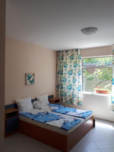 a bedroom with a bed and a window with curtains at Blue House - Синята къща in Obzor