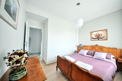a bedroom with a bed and a table with a vase of flowers at Poduszka Apartamenty Zdrojowe in Nałęczów