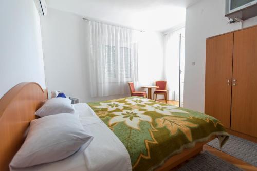 ein Schlafzimmer mit einem Bett mit einer grünen und weißen Decke in der Unterkunft Guesthouse Storelli in Lopud Island