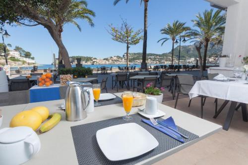 a table with food and drinks on a patio with palm trees at Los Geranios in Port de Soller