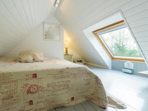 a bedroom with a bed in a attic with a window at Holiday home with private pool in Plouguin