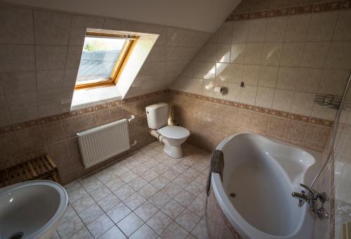a bathroom with a tub and a toilet and a sink at Penzion pod Šerákem in Ostružná