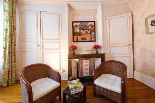 a living room with two chairs and a fireplace at Amphore du Berry in Saint-Amand-Montrond