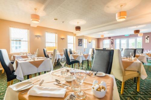 uma sala de jantar com mesas, cadeiras e copos em Pandora Hotel em St Peter Port