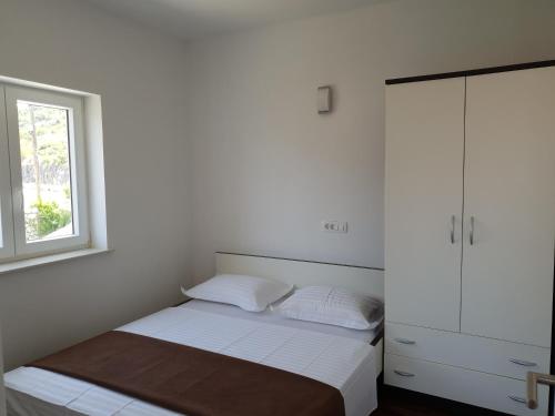 a white bedroom with a bed and a window at Apartments Mia Bilo in Podgreben