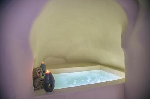 a bath tub with two vases and two candles at Morfi Cave House in Oia