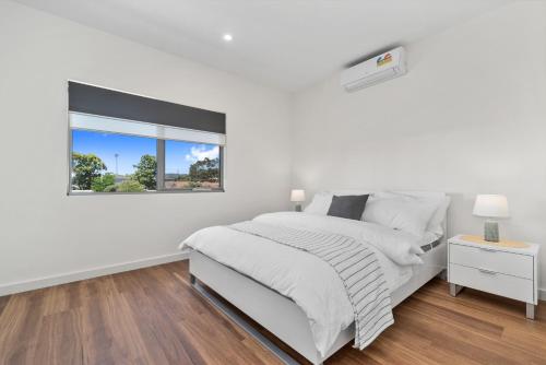 a white bedroom with a bed and a window at Rosewater Townhouses Dromana in Dromana