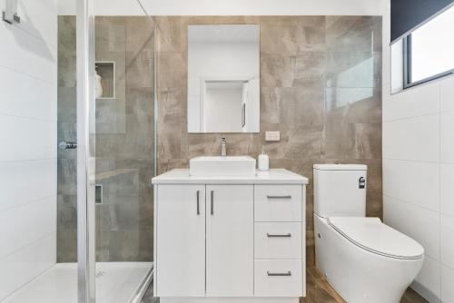 a white bathroom with a sink and a toilet at Rosewater Townhouses Dromana in Dromana