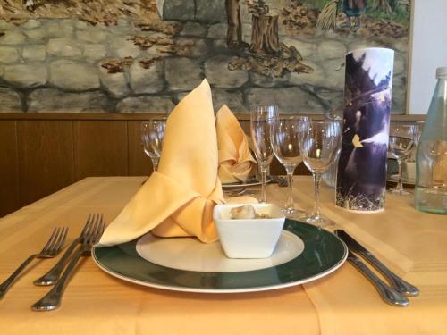 a table with a plate with a napkin and wine glasses at Hotel Vittoria in Folgaria