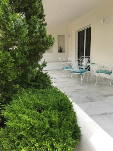 eine Terrasse mit Stühlen, Tischen und einem Baum in der Unterkunft Aggelikis House in Spáta
