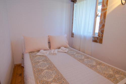 a bed with two slippers on it with a window at Loredana 1 in Veli Lošinj
